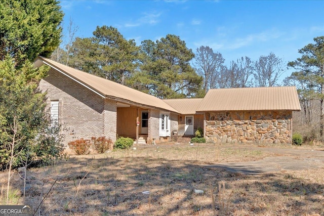 exterior space featuring stone siding, brick siding, and metal roof