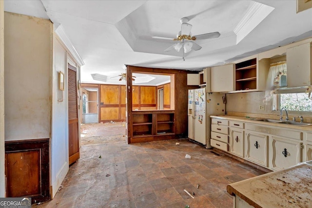 kitchen featuring open shelves, a tray ceiling, a sink, and cream cabinetry