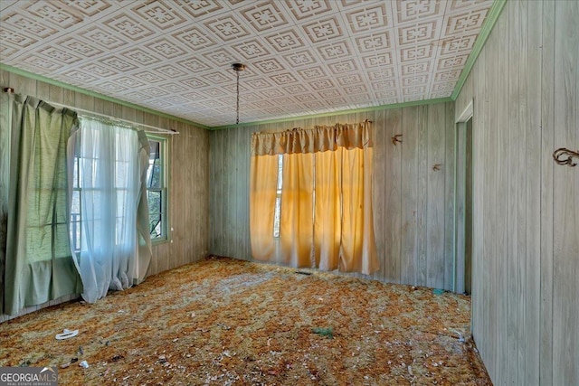 unfurnished room with an ornate ceiling, crown molding, and wooden walls