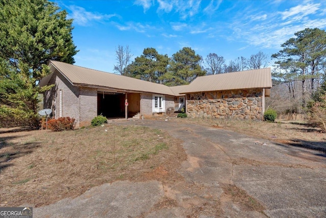 view of front of property with metal roof, brick siding, and driveway