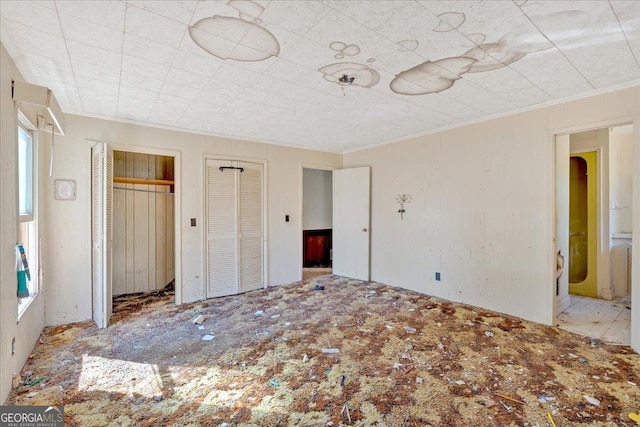 unfurnished bedroom featuring crown molding and two closets