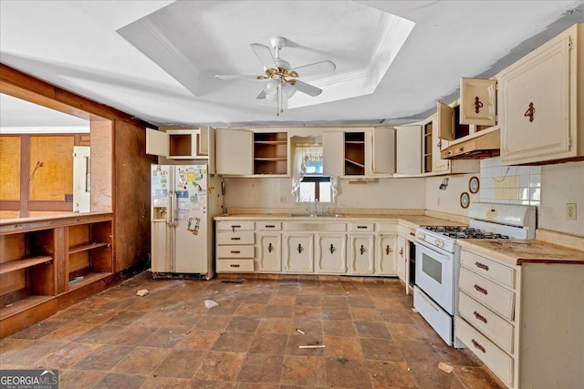 kitchen with white appliances, a raised ceiling, cream cabinetry, open shelves, and a sink