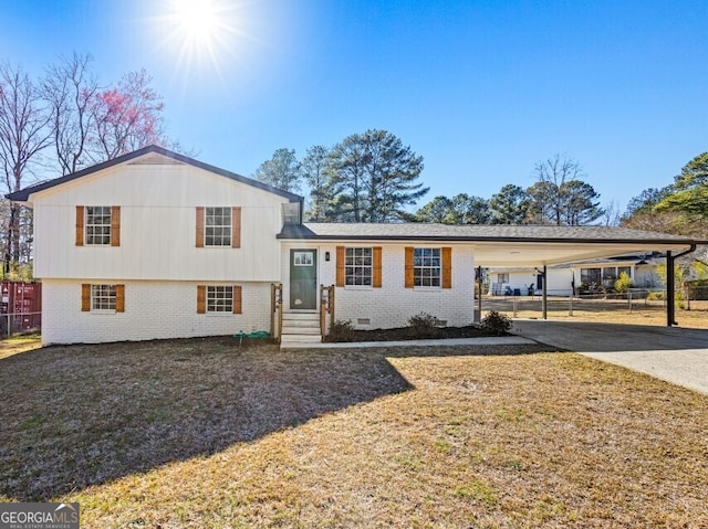 tri-level home featuring brick siding, crawl space, fence, an attached carport, and driveway