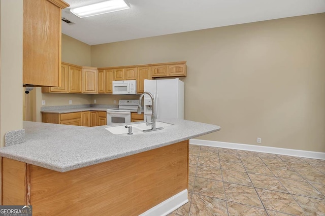 kitchen featuring baseboards, light countertops, a peninsula, white appliances, and a sink