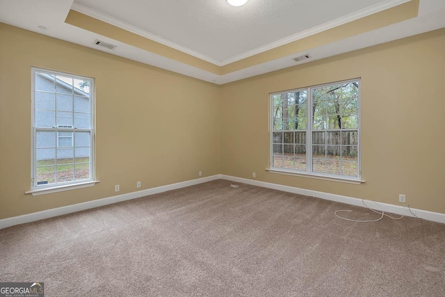 empty room featuring visible vents, baseboards, carpet, crown molding, and a raised ceiling