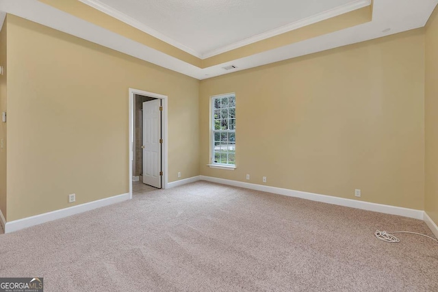 unfurnished room with baseboards, a raised ceiling, light colored carpet, and ornamental molding