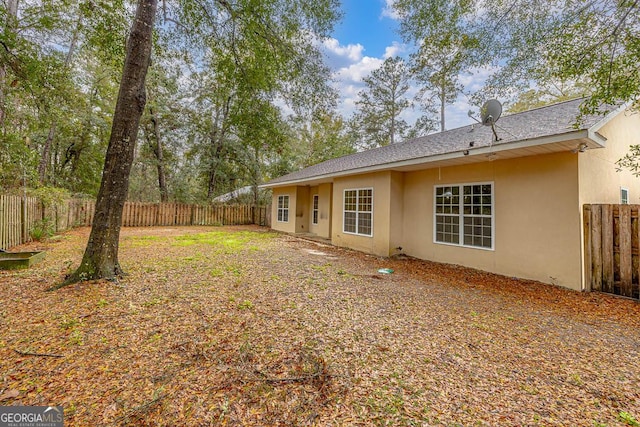 rear view of house featuring stucco siding and a fenced backyard