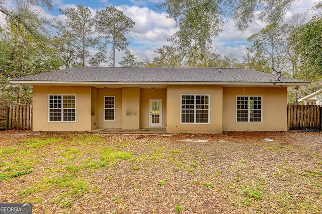 rear view of property with stucco siding and fence