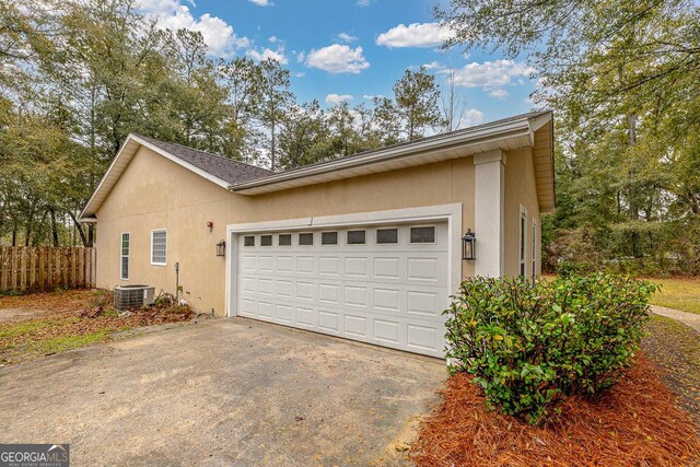 view of side of property with stucco siding, a garage, driveway, and fence