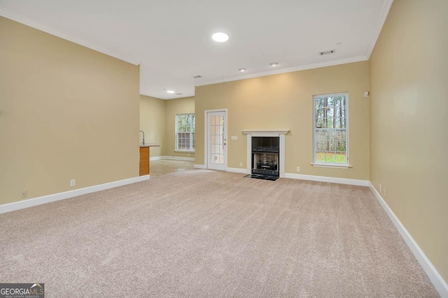 unfurnished living room featuring visible vents, a fireplace with flush hearth, light carpet, crown molding, and baseboards