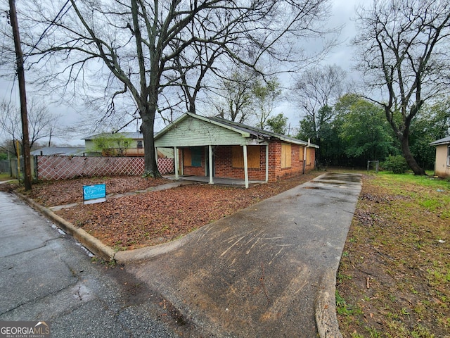 view of front of home featuring a porch, fence, and brick siding