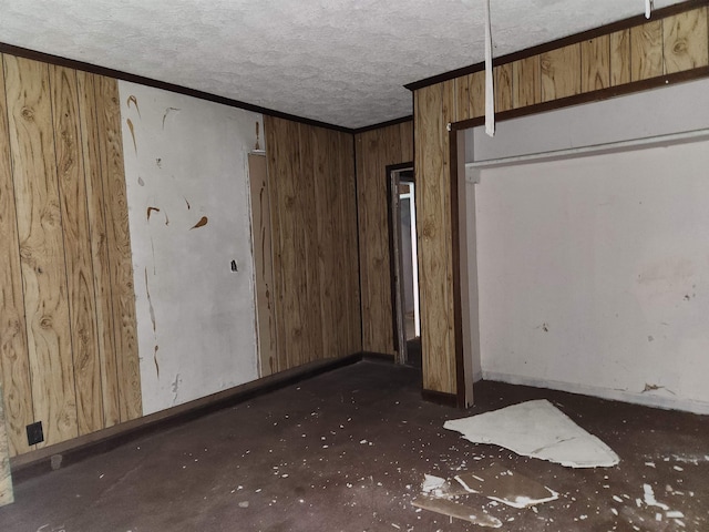 unfurnished bedroom with baseboards, a textured ceiling, wood walls, and ornamental molding