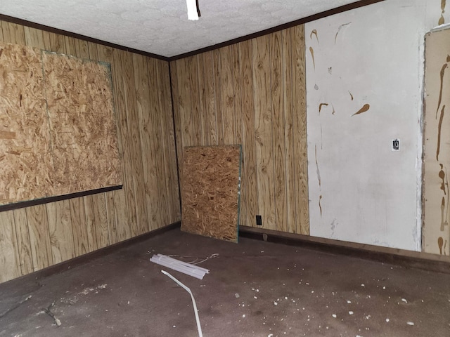 unfurnished room featuring wooden walls, ornamental molding, and a textured ceiling