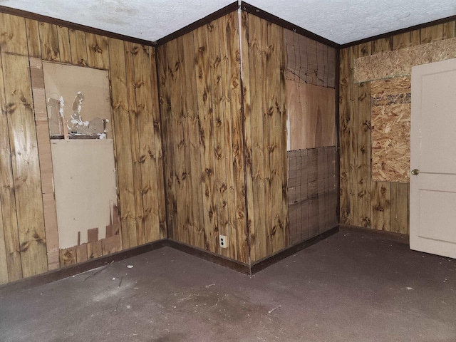 empty room featuring baseboards, wood walls, and a textured ceiling