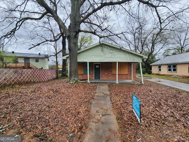 bungalow with brick siding, a porch, and fence