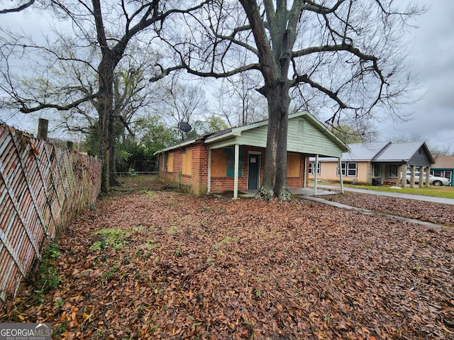 view of property exterior with brick siding, covered porch, and fence