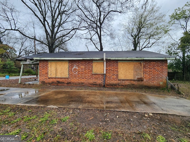 rear view of house with brick siding and a patio