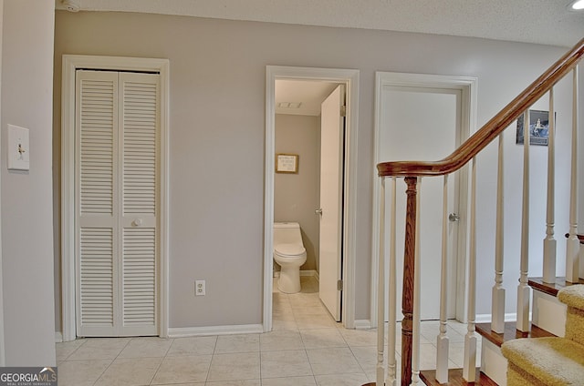 interior space with stairs, a textured ceiling, baseboards, and light tile patterned floors