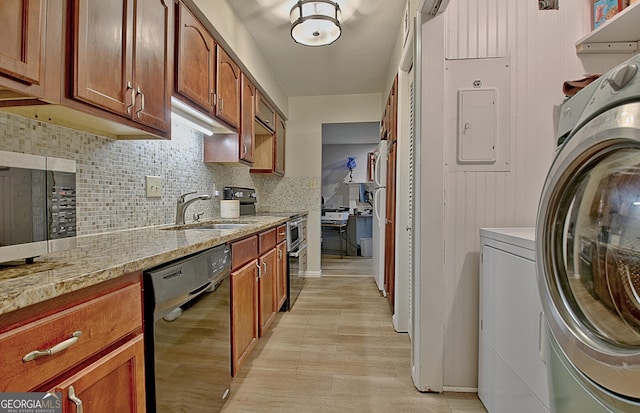 kitchen with light wood finished floors, tasteful backsplash, appliances with stainless steel finishes, a sink, and washer and dryer