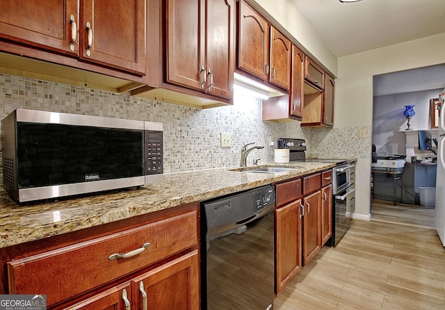 kitchen featuring light stone countertops, stainless steel appliances, a sink, brown cabinets, and decorative backsplash