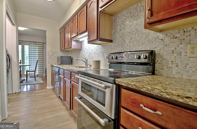 kitchen with backsplash, light wood-style flooring, brown cabinetry, a sink, and double oven range