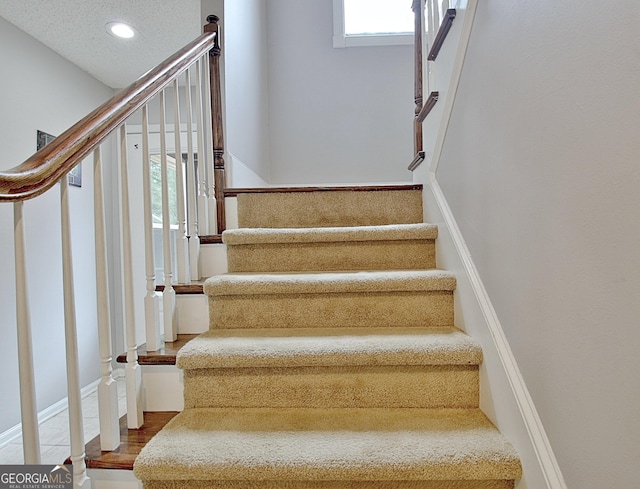 stairs with wood finished floors and recessed lighting