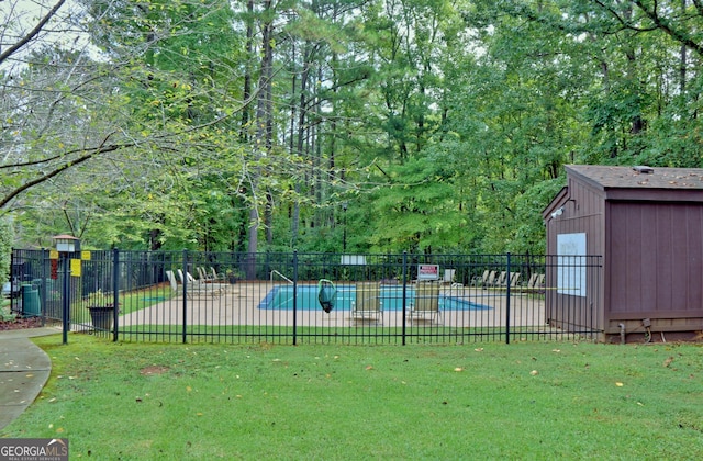 community pool with an outbuilding, a lawn, a patio area, and fence