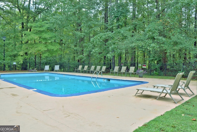 community pool with a patio area and fence