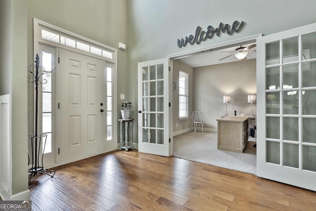 foyer with baseboards, ceiling fan, hardwood / wood-style flooring, french doors, and a towering ceiling