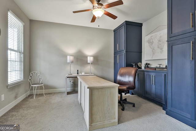 office space with a ceiling fan, light colored carpet, and baseboards