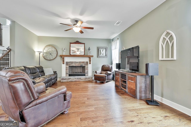 living area with visible vents, baseboards, a fireplace, wood finished floors, and a ceiling fan