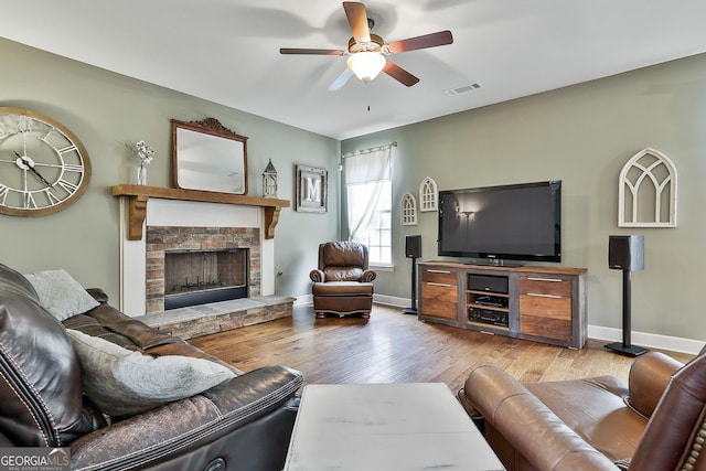 114 Austin Storey Cir, Newnan, GA 30263 - living room featuring ceiling fan, wood finished floors, baseboards, and a stone fireplace