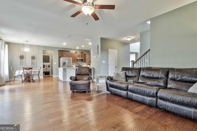 living area with stairway, wood finished floors, baseboards, separate washer and dryer, and ceiling fan