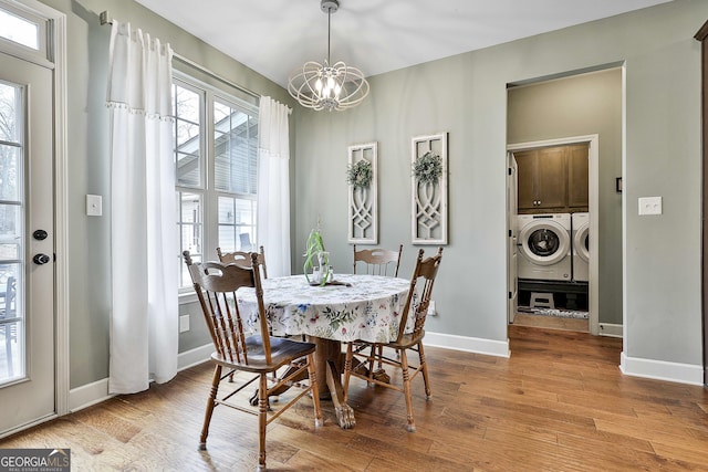 dining area with washer and dryer, light wood-type flooring, baseboards, and a chandelier