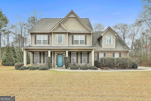 view of front of home with a front yard, covered porch, and roof with shingles