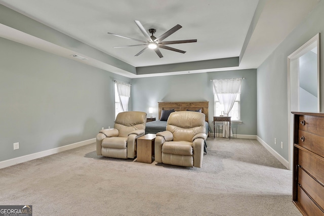 carpeted bedroom with visible vents, baseboards, a raised ceiling, and a ceiling fan