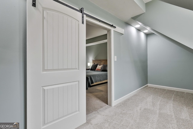 hall with carpet flooring, baseboards, and a barn door