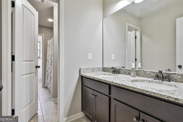 full bathroom featuring a sink, baseboards, double vanity, and tile patterned flooring