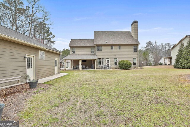 back of property featuring a patio, a yard, and a chimney