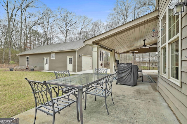 view of patio / terrace with an outbuilding, an attached garage, ceiling fan, and outdoor dining space