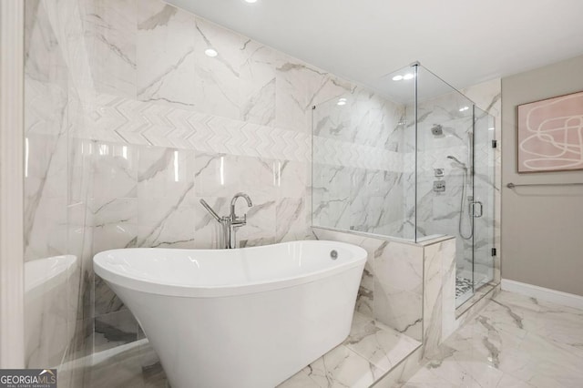 full bath with marble finish floor, a marble finish shower, stone wall, and a freestanding tub