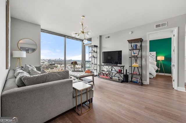 living area with expansive windows, wood finished floors, visible vents, and an inviting chandelier