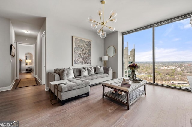 living room with a view of city, a notable chandelier, expansive windows, wood finished floors, and baseboards