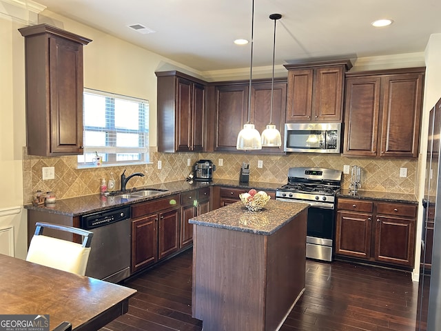 kitchen with dark wood finished floors, stainless steel appliances, visible vents, a sink, and a kitchen island