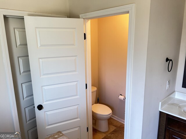 bathroom with toilet, vanity, and baseboards