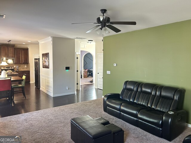 living area with a ceiling fan, visible vents, arched walkways, dark carpet, and dark wood-type flooring