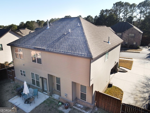 back of property with a patio area, fence, and roof with shingles