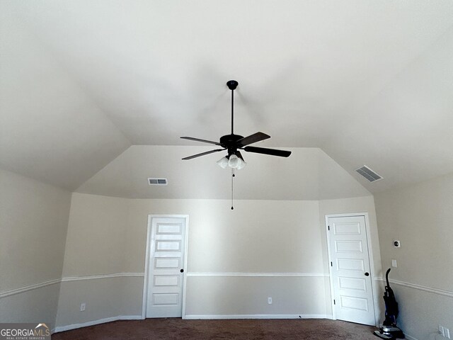 unfurnished room featuring visible vents, lofted ceiling, and dark carpet