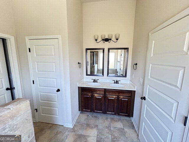 bathroom featuring double vanity, a sink, and baseboards