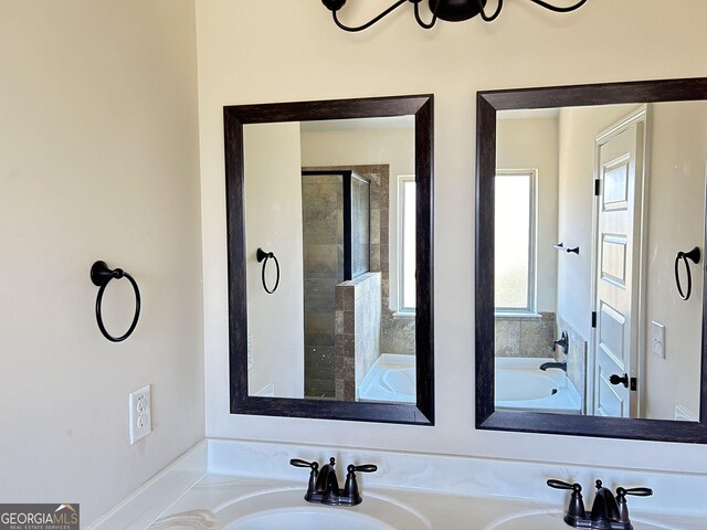 bathroom with a bath, double vanity, a sink, and tiled shower